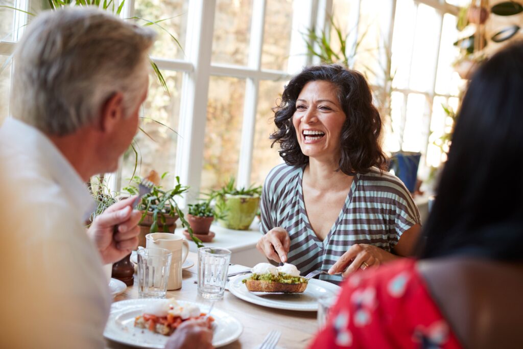 Woman smiling while eating at restaurant with friends